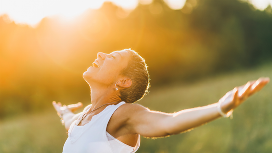 femme les bras écartés qui respire dans un champ